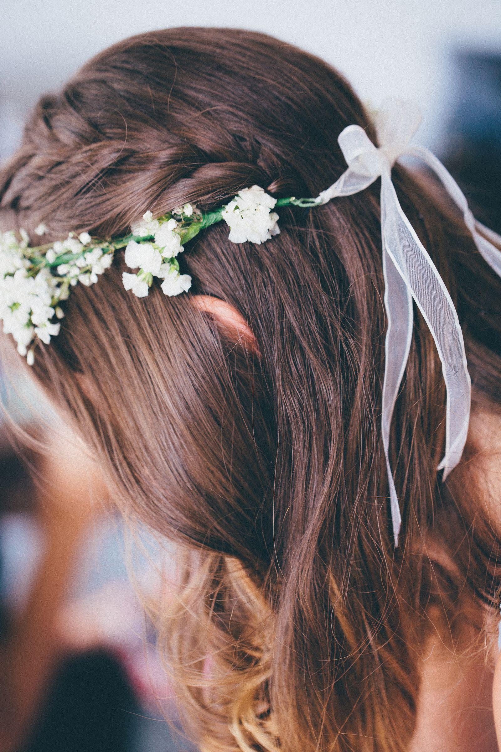 Close-up of a braided crown hairstyle woven with white flowers