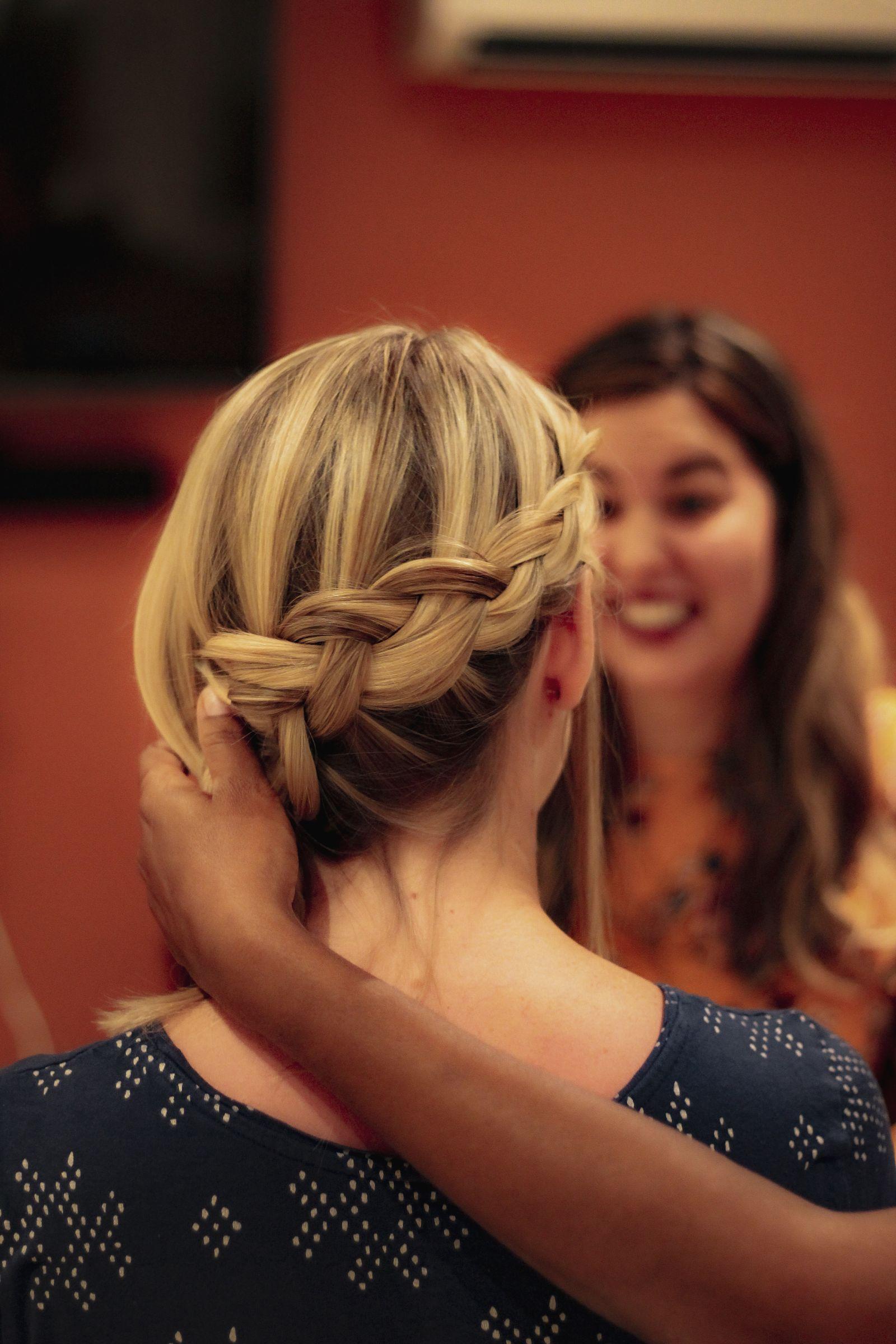 Hairstylist finishing a braided hairstyle on a client, candid styling moment