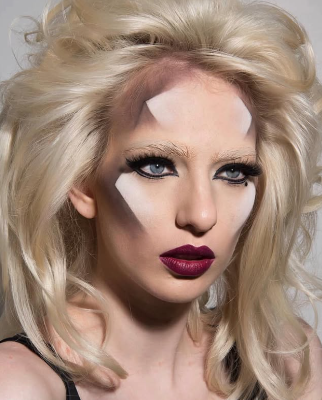 Graphic avant-garde eye makeup with sharp geometric white shapes across the brow and cheek