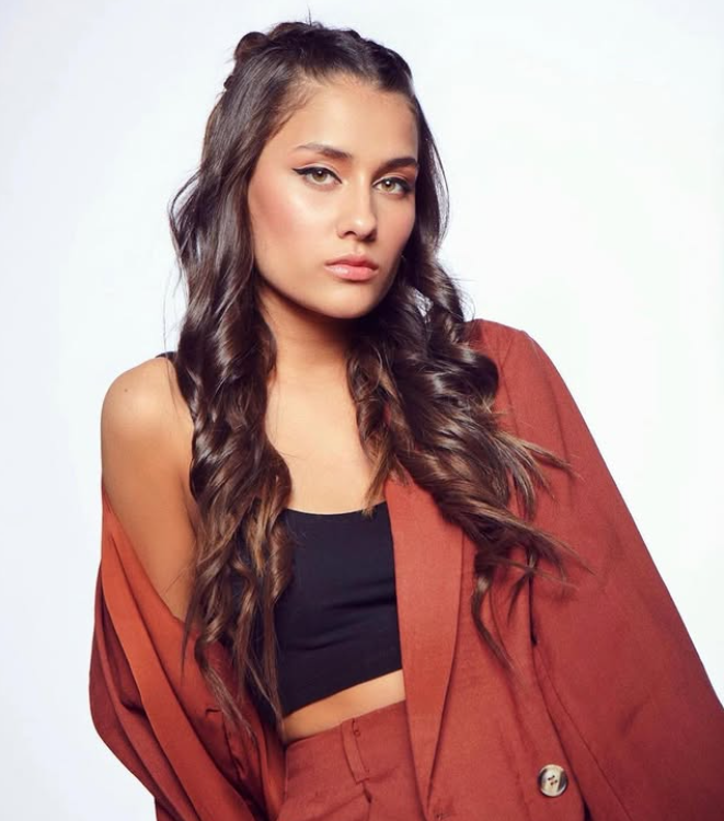 Studio beauty portrait with soft waves and warm glam makeup, rust-toned wardrobe