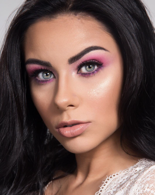 Close-up beauty portrait with fuchsia and purple gradient eyeshadow, dewy highlighted skin and nude lip