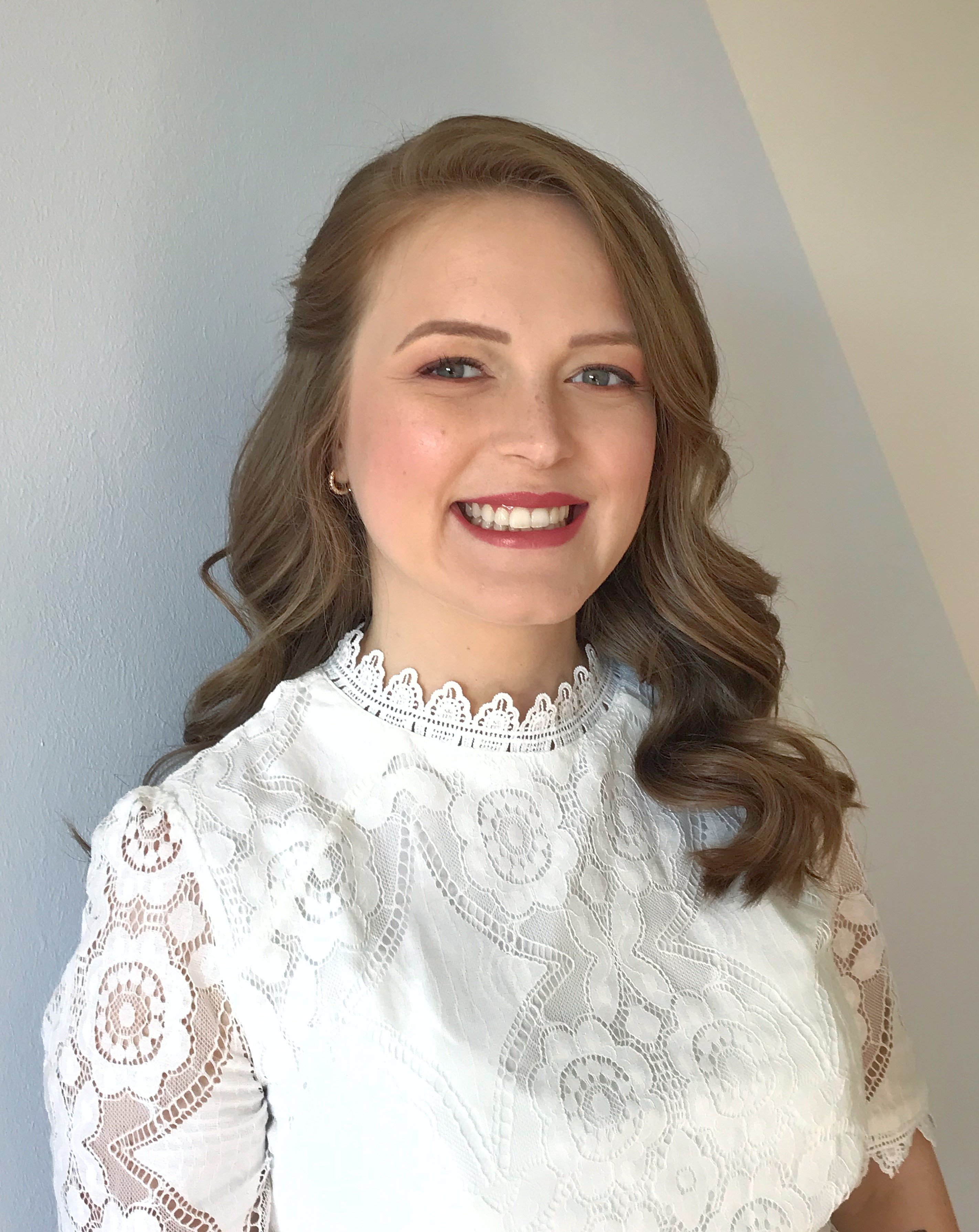 Bride with soft glamorous curls and rosy bridal makeup in a high-neck lace blouse