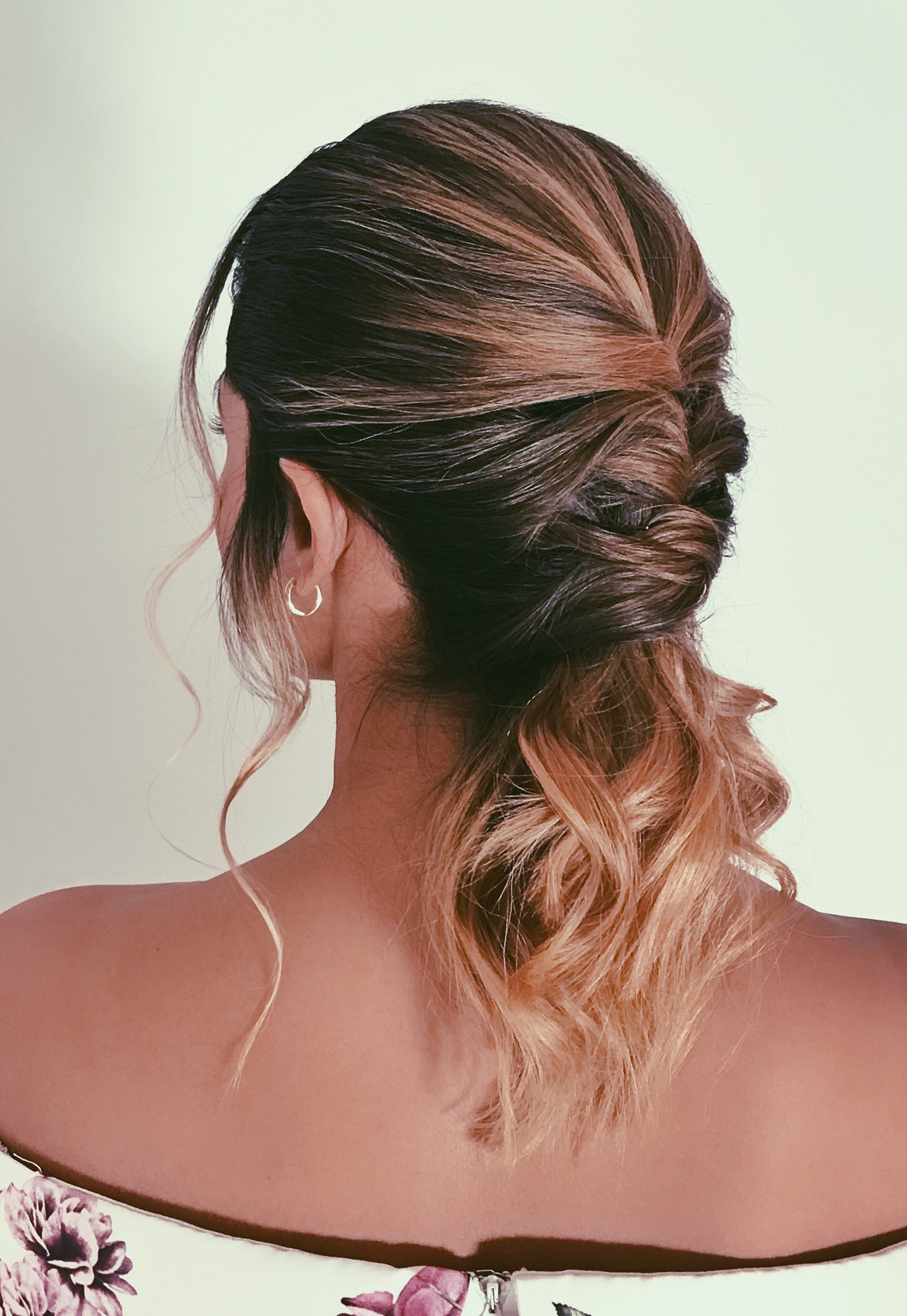 Back view of a textured, twisted bridal half-up ponytail with soft waves